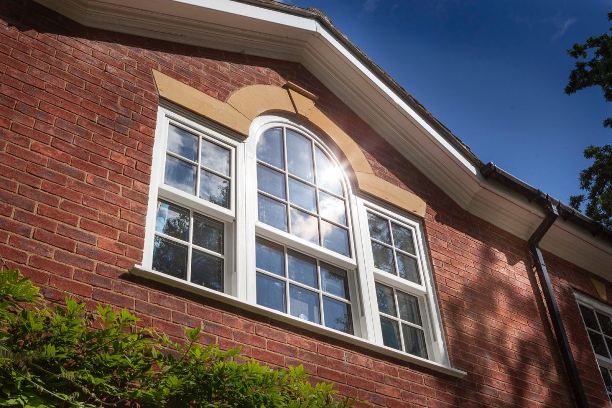 White Arched and flat Georgian uPVC sliding sash windows in white on a red brick building