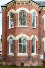 Brick home featuring six arched white uPVC sliding sash windows in symmetrical layout