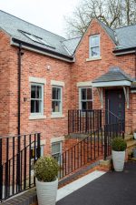 Red brick home featuring multiple agate grey uPVC sliding sash windows