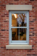 Agate grey uPVC sash window fitted in red brick wall of house