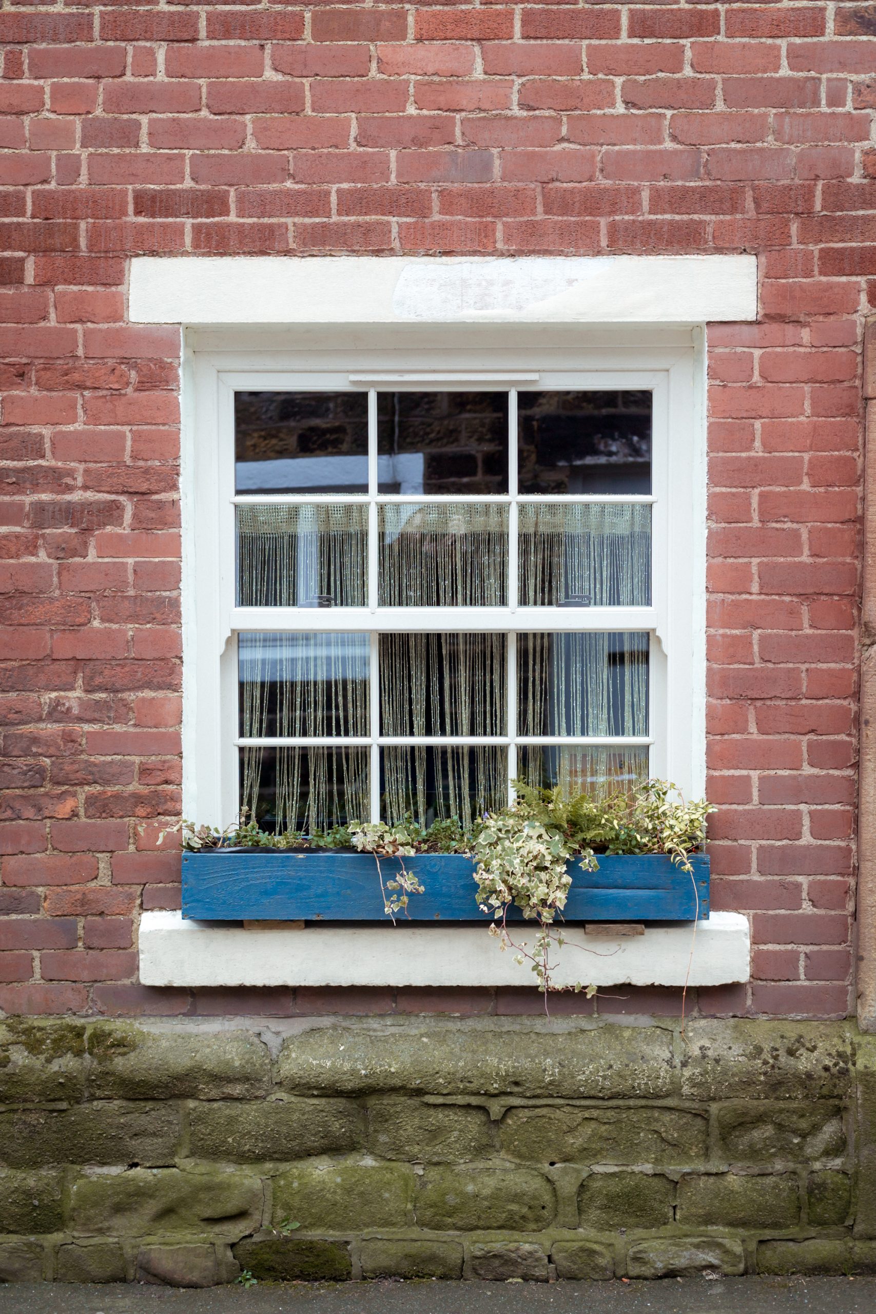 Close-up of cream woodgrain uPVC sliding sash window with ovolo profile.