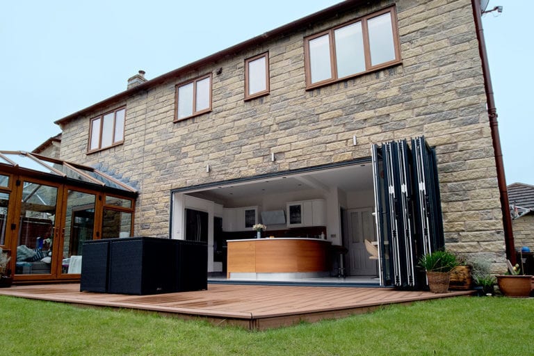 Wide open large aluminium bifold doors with a wooden patio