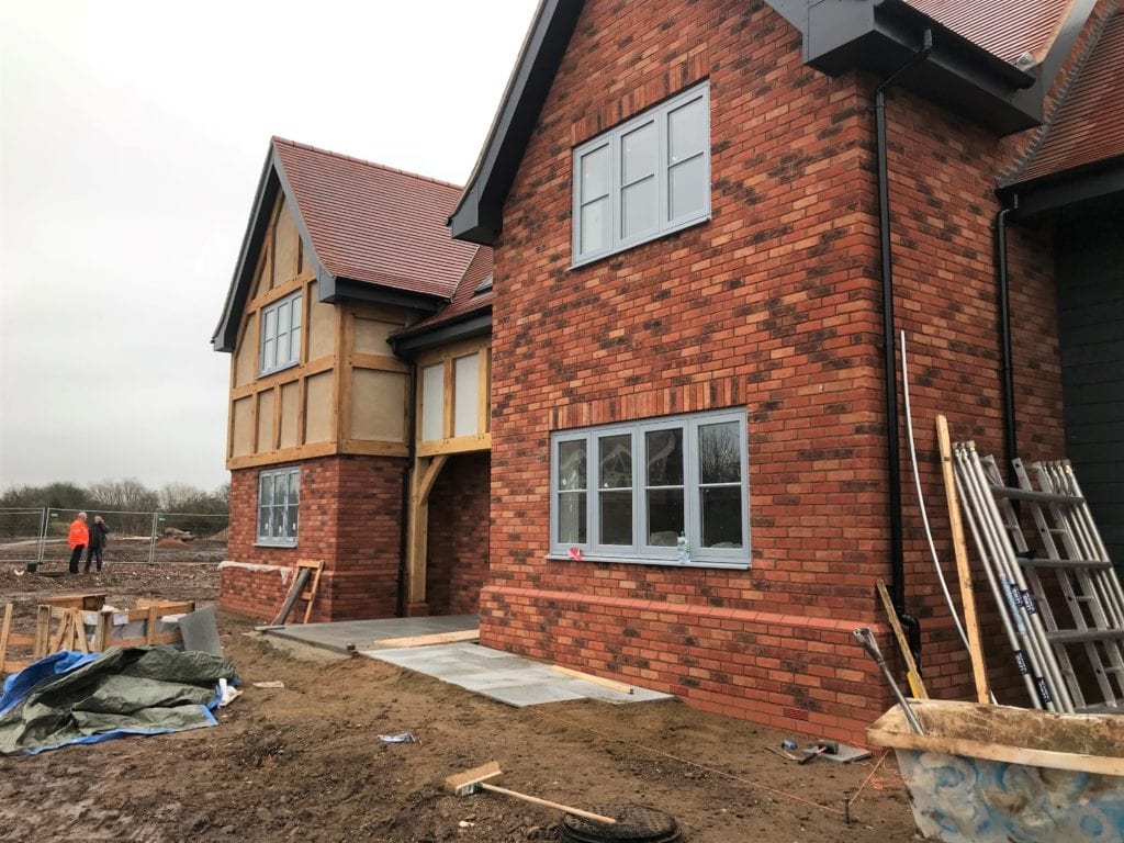 dark grey casement windows on a red brick house undergoing construction