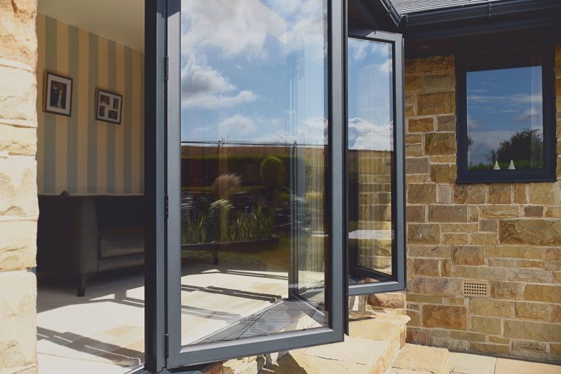 Grey aluminium bi-fold doors, accompanied by a mention of the 2022 changes to building regulations for doors and windows. Explore this contemporary door option while staying informed about regulatory updates.