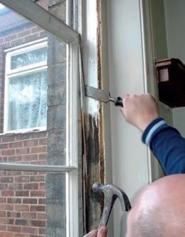 Man Chiselling sash window for replacement