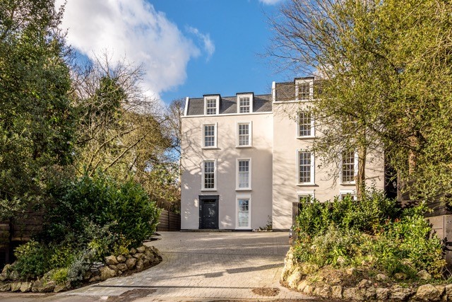 A grand detached home featuring white woodgrain uPVC sliding sash windows with Georgian bars