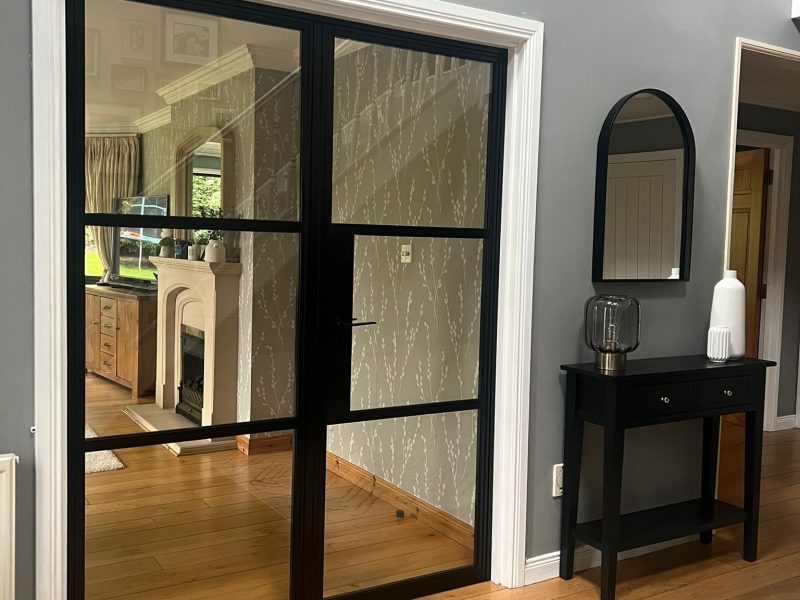 Slimline black aluminium internal doors with a steel-look design, dividing a contemporary living space