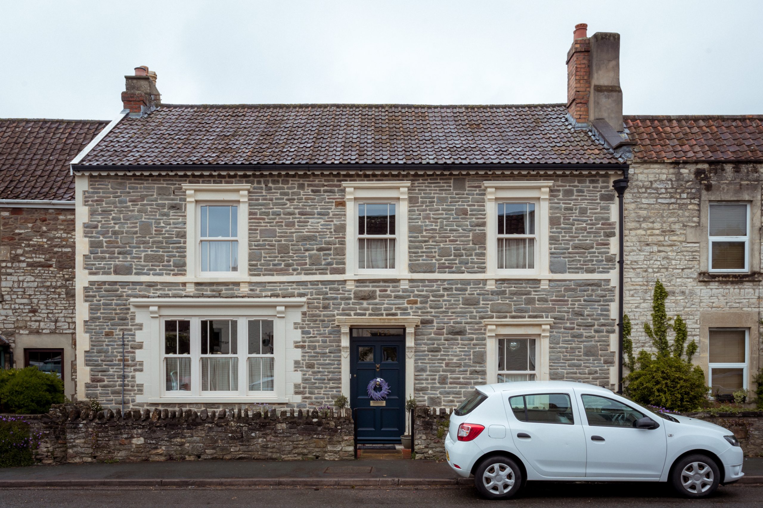 Front view of Georgian house with bespoke shop front style window and cream woodgrain finish sliding sash windows