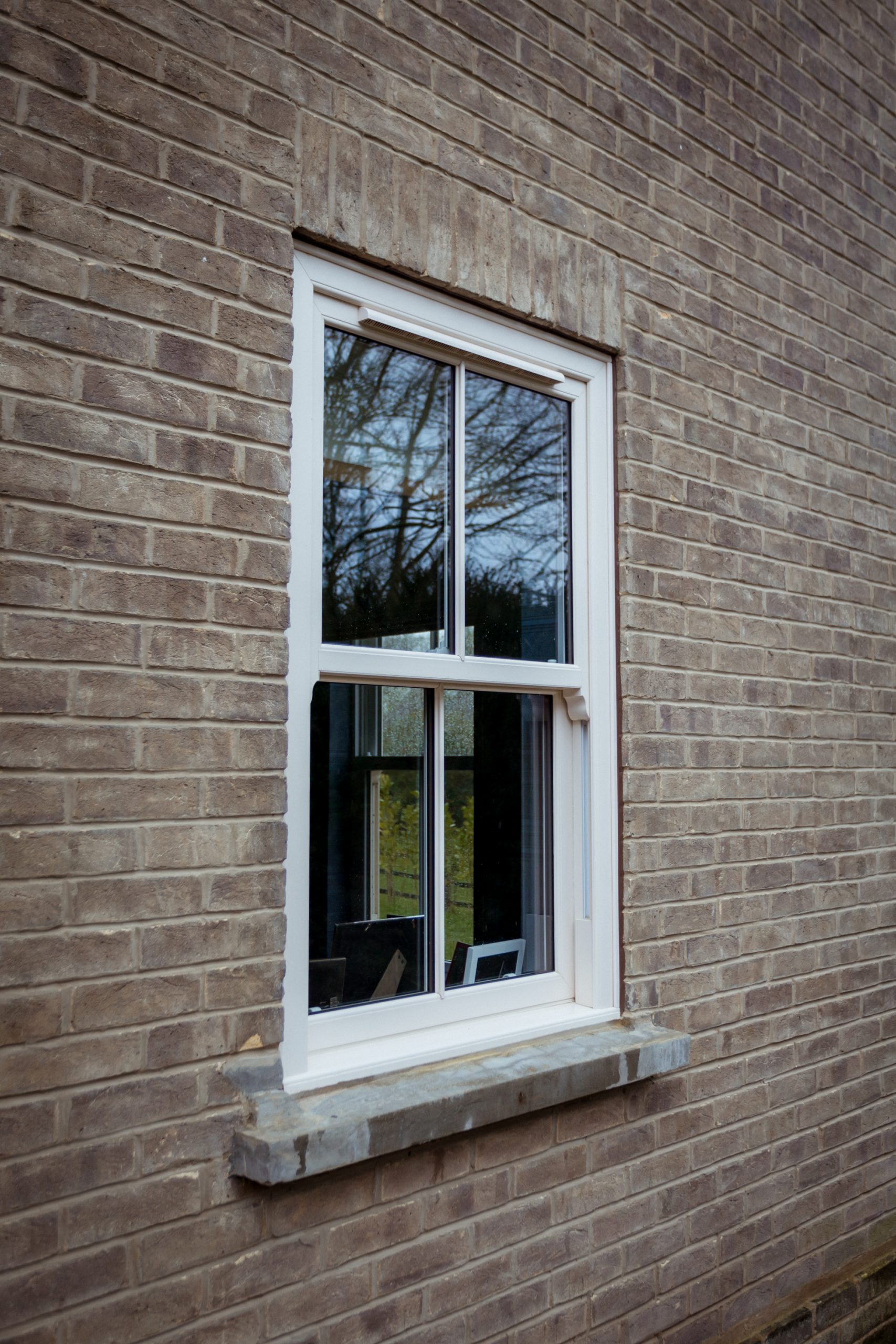 Close-up of cream vertical sliders featuring a single astragal bar and white hardware.