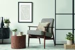 Scandinavian-style living room featuring a design armchair, black poster frame, wooden stool, and modern decor