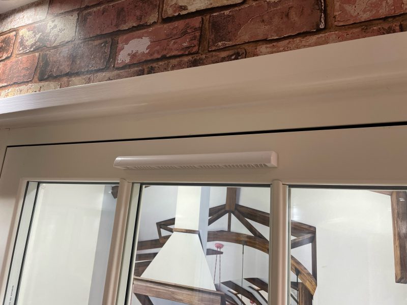 Close-up of a trickle vent on a uPVC flush sash window, providing airflow while maintaining a closed window