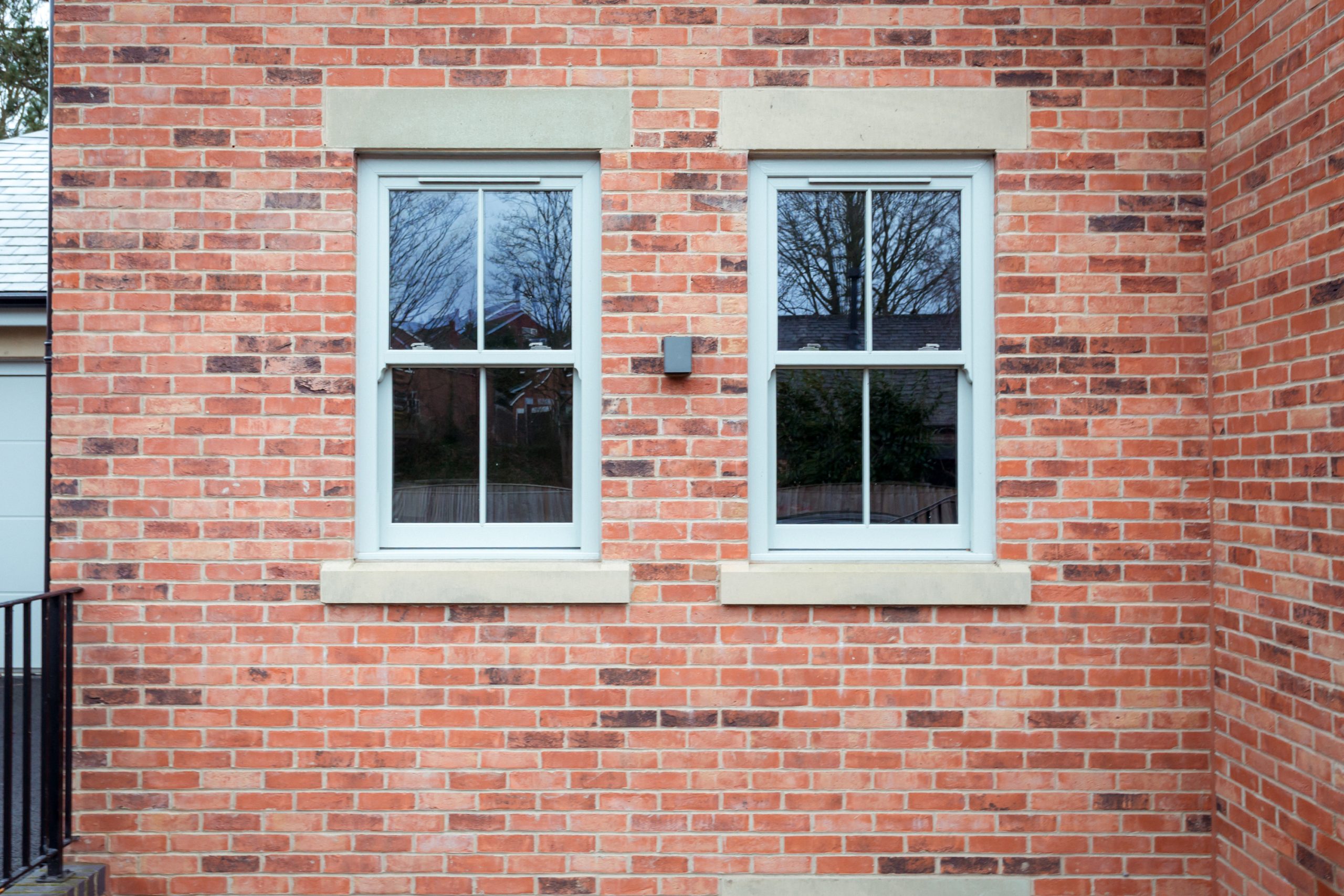 Two Agate Grey uPVC sash windows on a brick wall, part of AJ Roberts’ Park Lane project