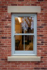Agate grey uPVC sash window fitted in red brick wall of house