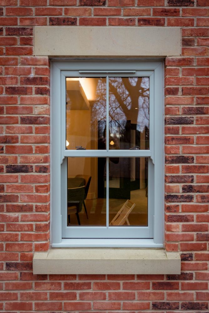 Agate grey uPVC sash window fitted in red brick wall of house