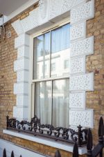 Cream uPVC sliding sash window fitted on exterior wall of a traditional home